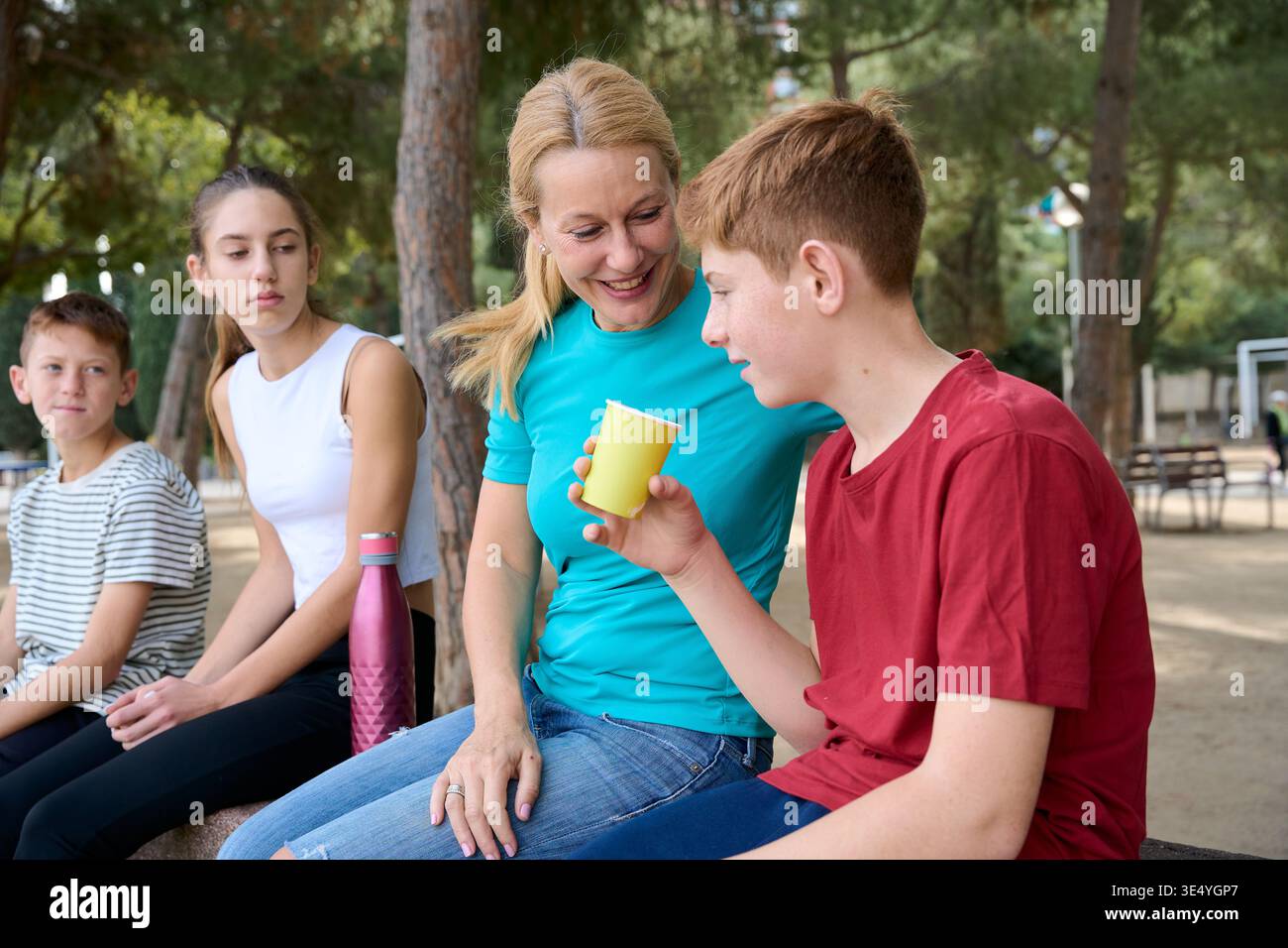 Mère et trois enfants se relaxant ensemble dans le parc Banque D'Images