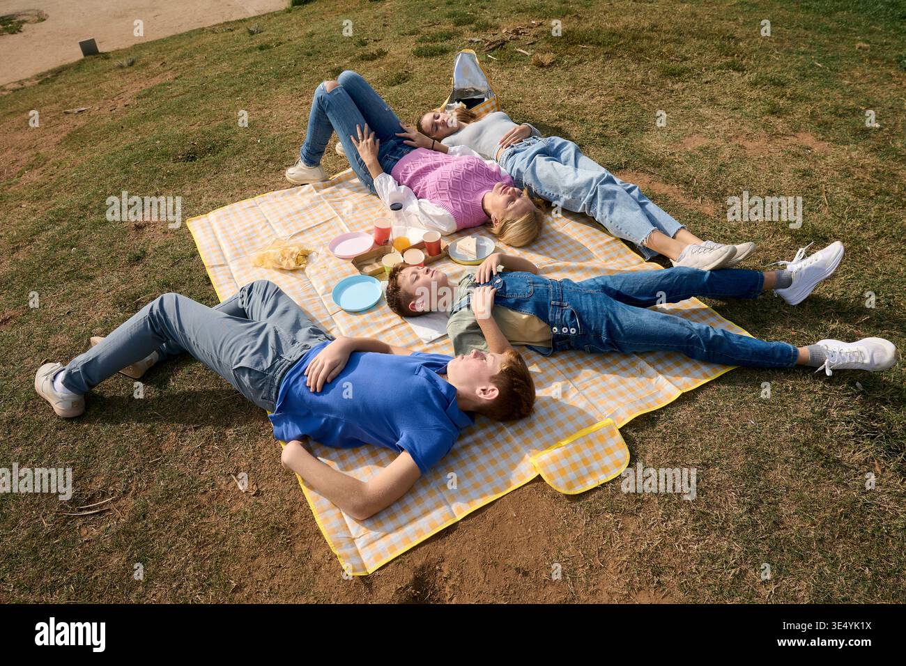 Mère et trois enfants se relaxant à l'extérieur sur une couverture de pique-nique Banque D'Images