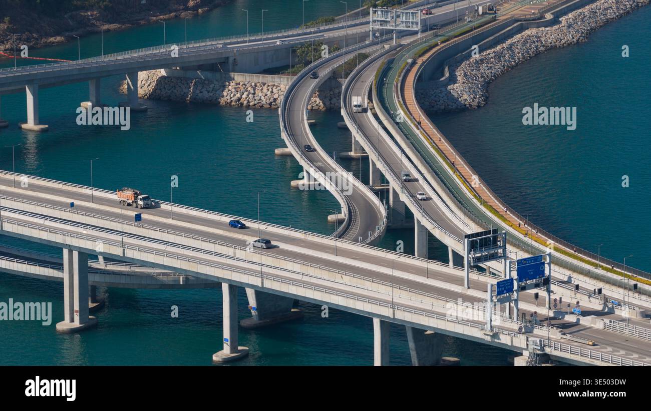 Vue aérienne du pont Cross Bay Link avec des rampes d'accès incurvées et des véhicules au-dessus de l'eau turquoise dans les nouveaux Territoires, Hong Kong. Banque D'Images