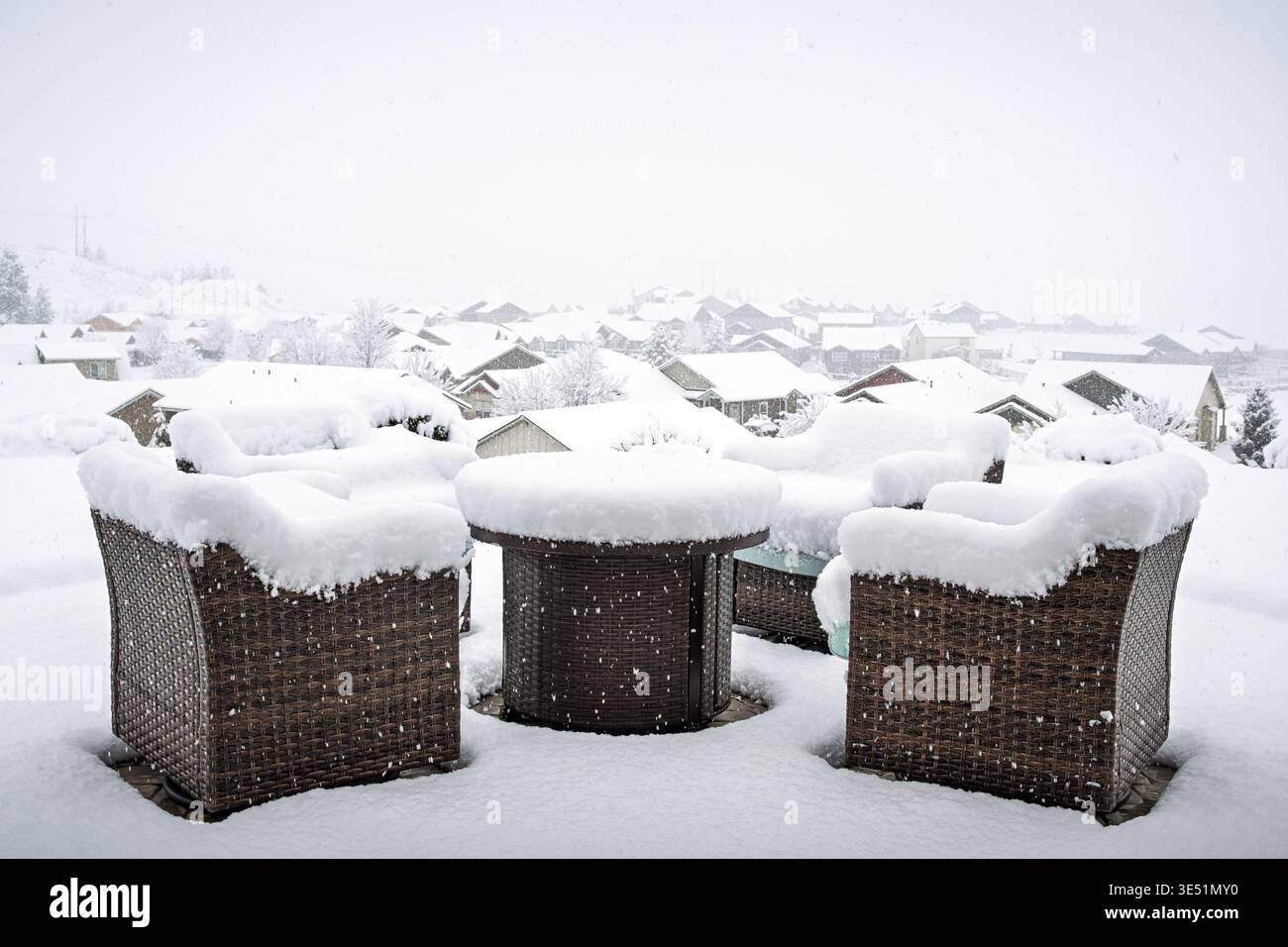 Un ensemble patio et un foyer couvert d'une quantité généreuse de neige fraîche sur une colline surplombant un quartier de banlieue pendant une tempête douce. Banque D'Images