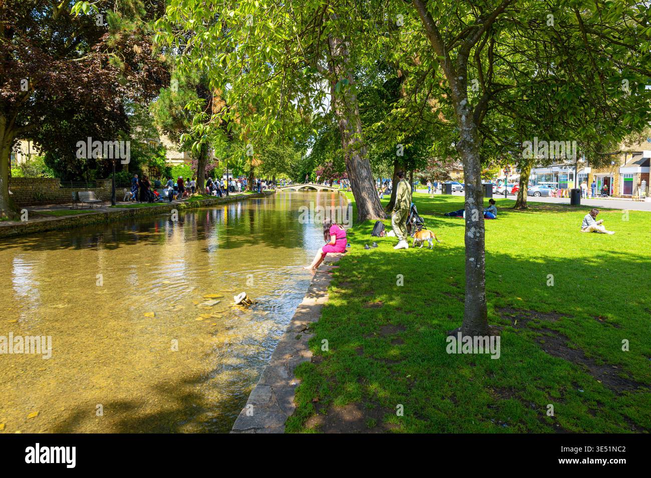 Les touristes profitent d'une journée d'automne ensoleillée le long de la rivière Windrush dans le charmant village Cotswold de Bourton-on-the-Water, en Angleterre. Banque D'Images
