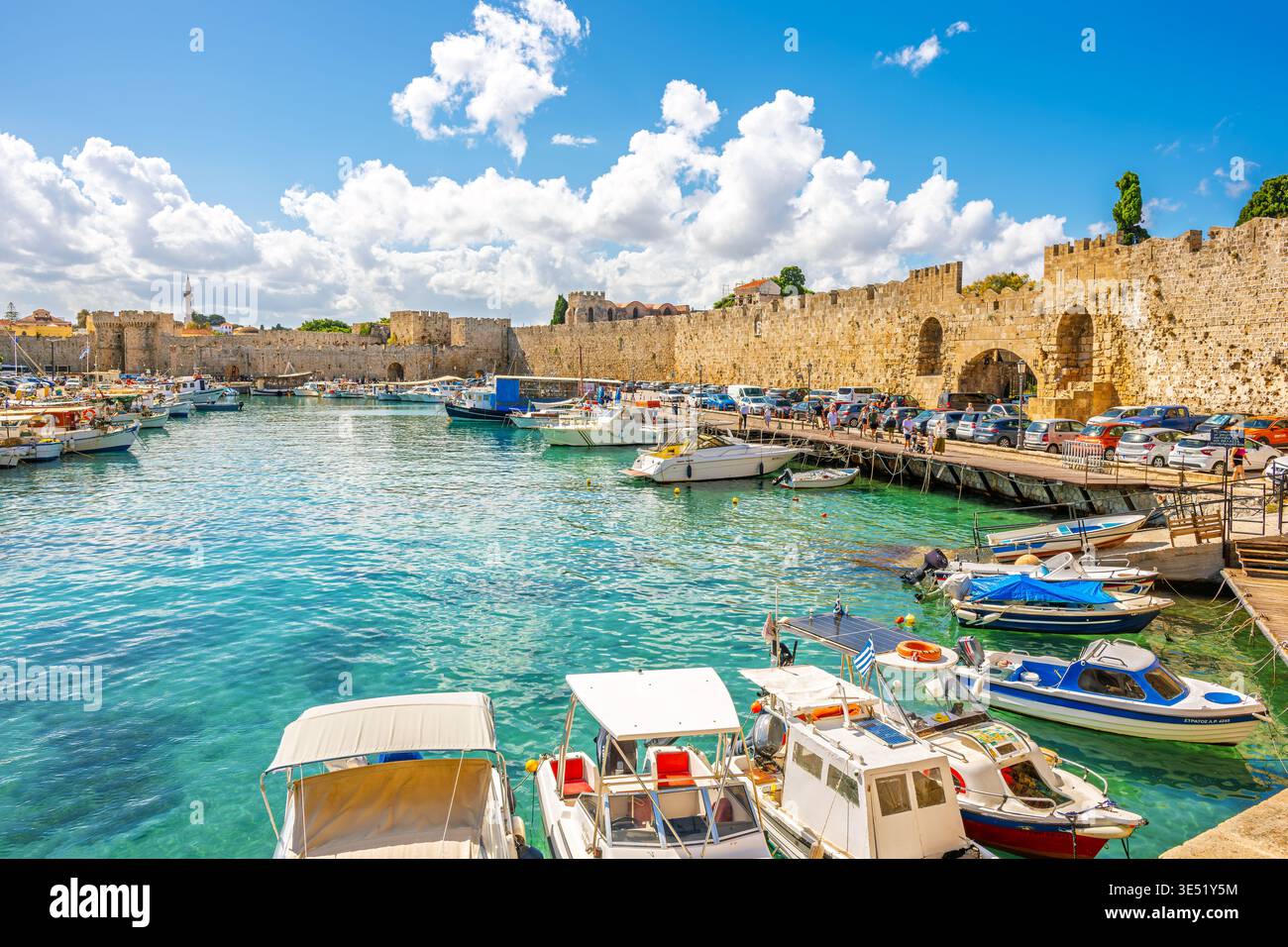 Des bateaux de pêche bordent l'ancien port de Mandraki le long des murs de défense et des portes du centre médiéval fortifié de Rhodes, en Grèce. Banque D'Images