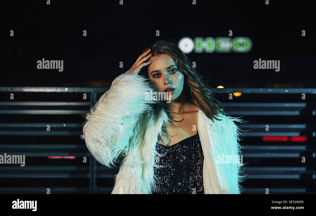 Portrait d'une jeune femme posant dehors la nuit portant des vêtements élégants Banque D'Images