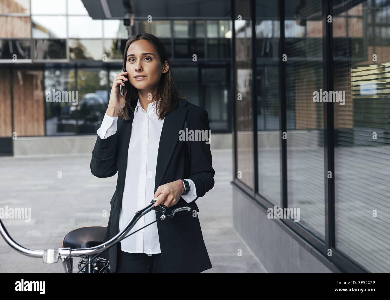 Jeune femme élégante dans des vêtements formels noirs avec vélo Banque D'Images