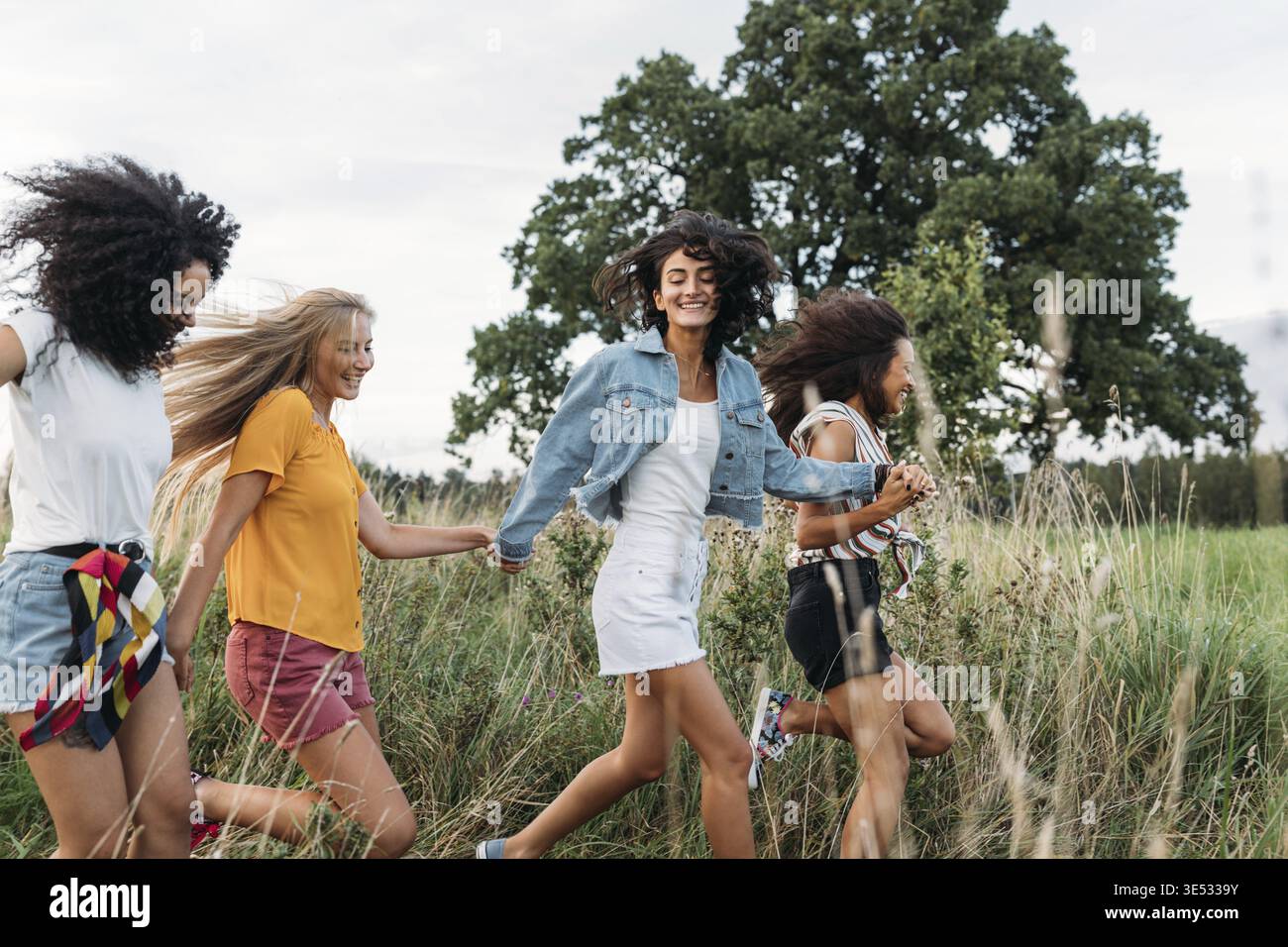 Groupe d'une femme heureuse qui court et saute à l'extérieur. Des amies qui s'amusent Banque D'Images