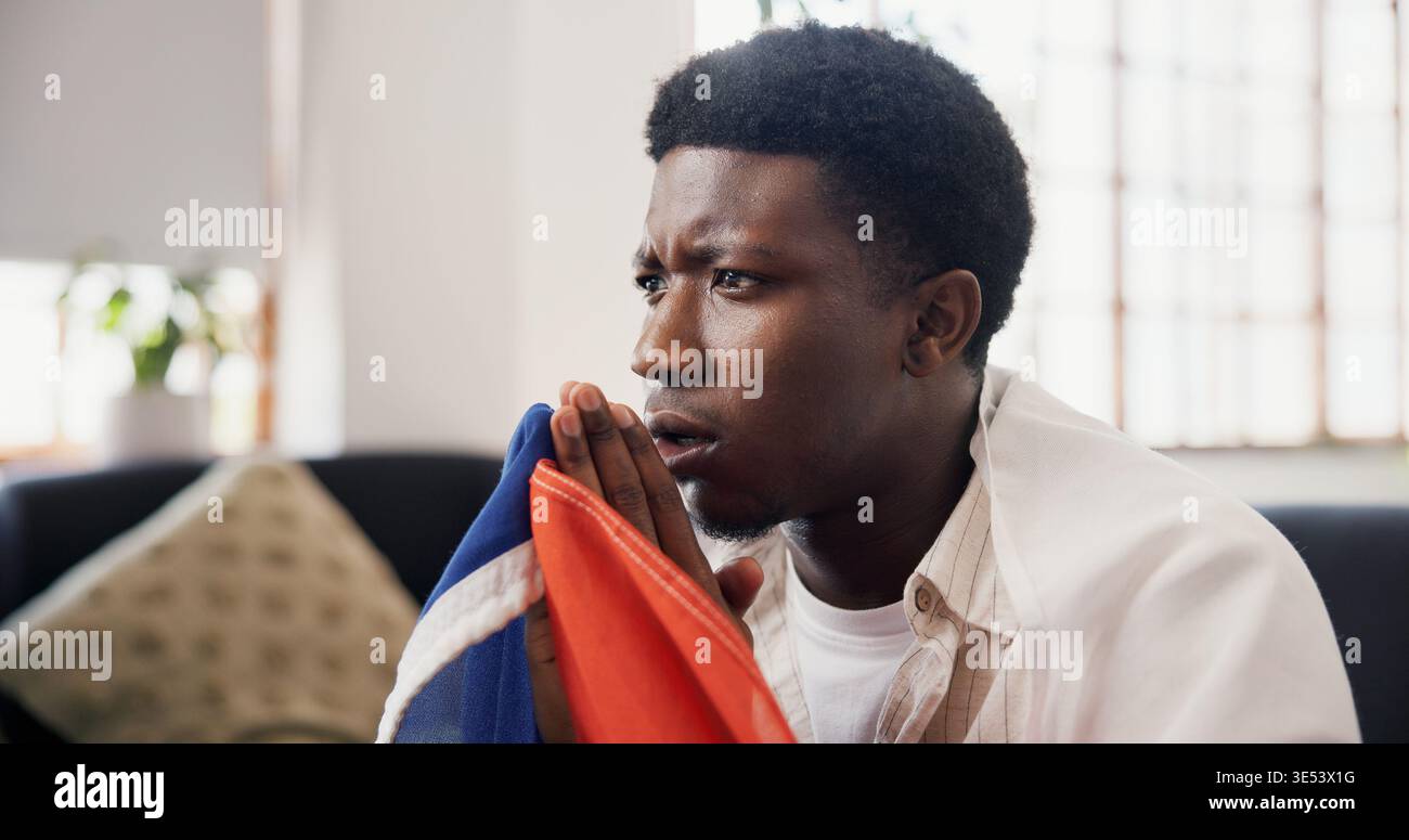 Homme, inquiétude et regarder la télévision à la maison avec match de sport, préoccupation et suspense pour la compétition de football. Personne noire, stress et nerveux dans le salon avec Banque D'Images