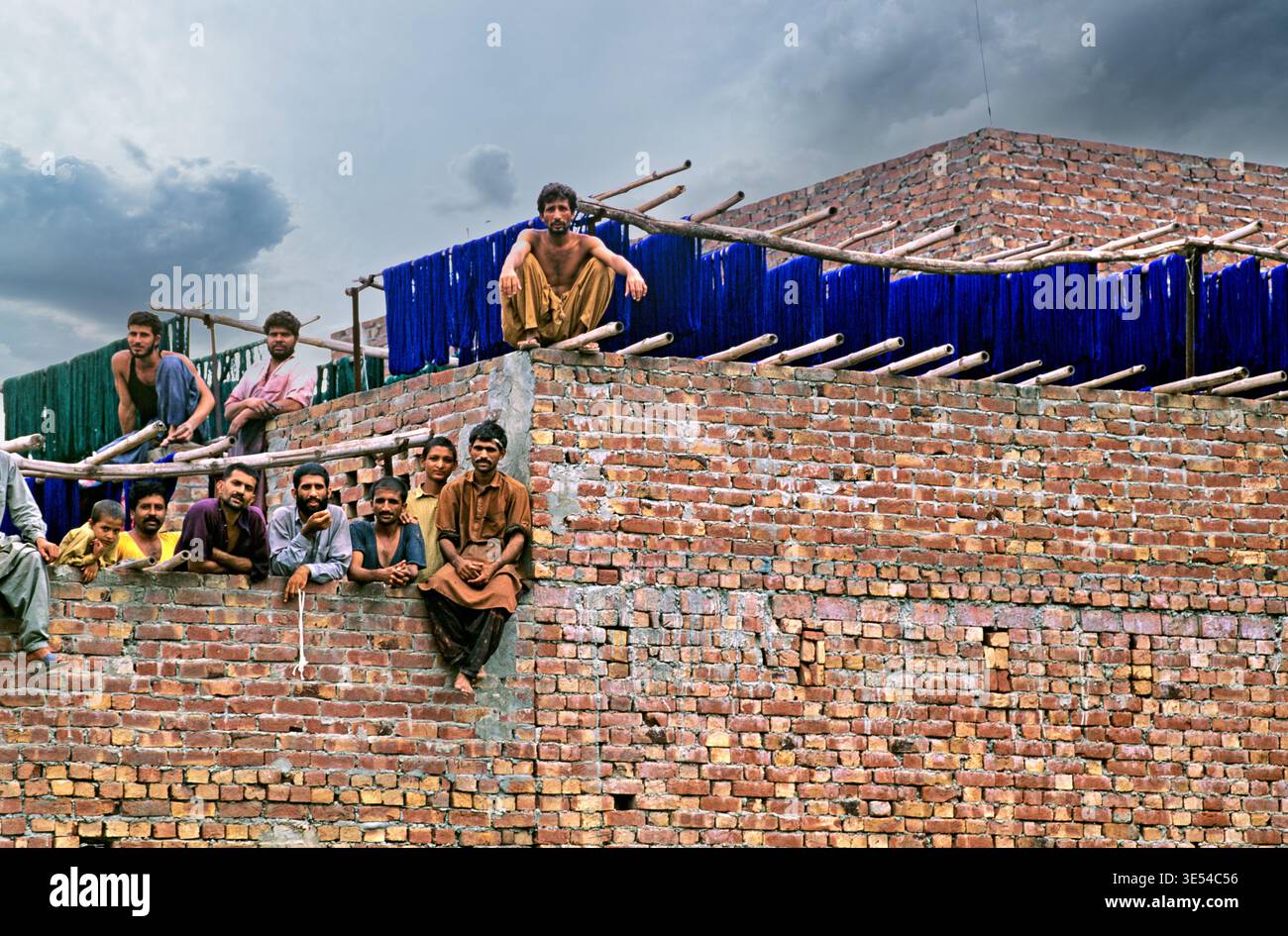 Les ouvriers font une pause sur un chantier de construction à Lahore. Ils se détendent sur des murs de briques tout en discutant et en profitant de leur temps libre ensemble. Banque D'Images