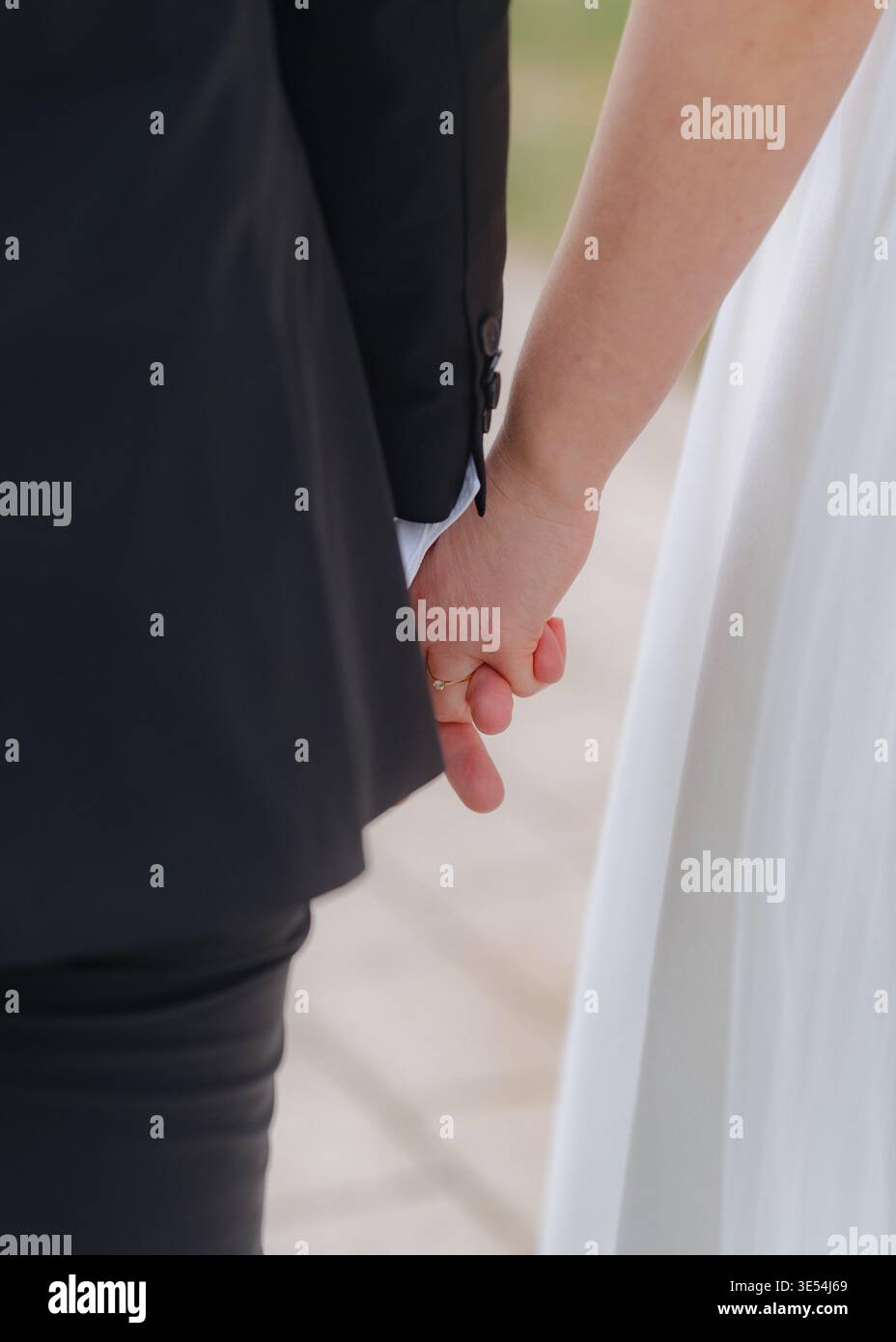 Gros plan de mariés se tenant par la main. Symbole d'amour, de confiance et d'engagement. Moment de mariage émotionnel avec lumière naturelle douce. Banque D'Images