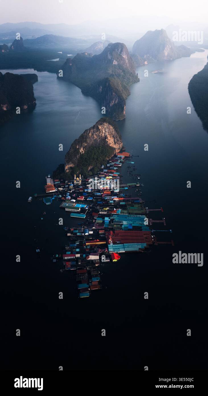 Vue aérienne du village flottant sur pilotis avec des toits colorés nichés contre un karst calcaire dans le parc national d'Ao Phang Nga, Tambon Ko Panyi, Banque D'Images