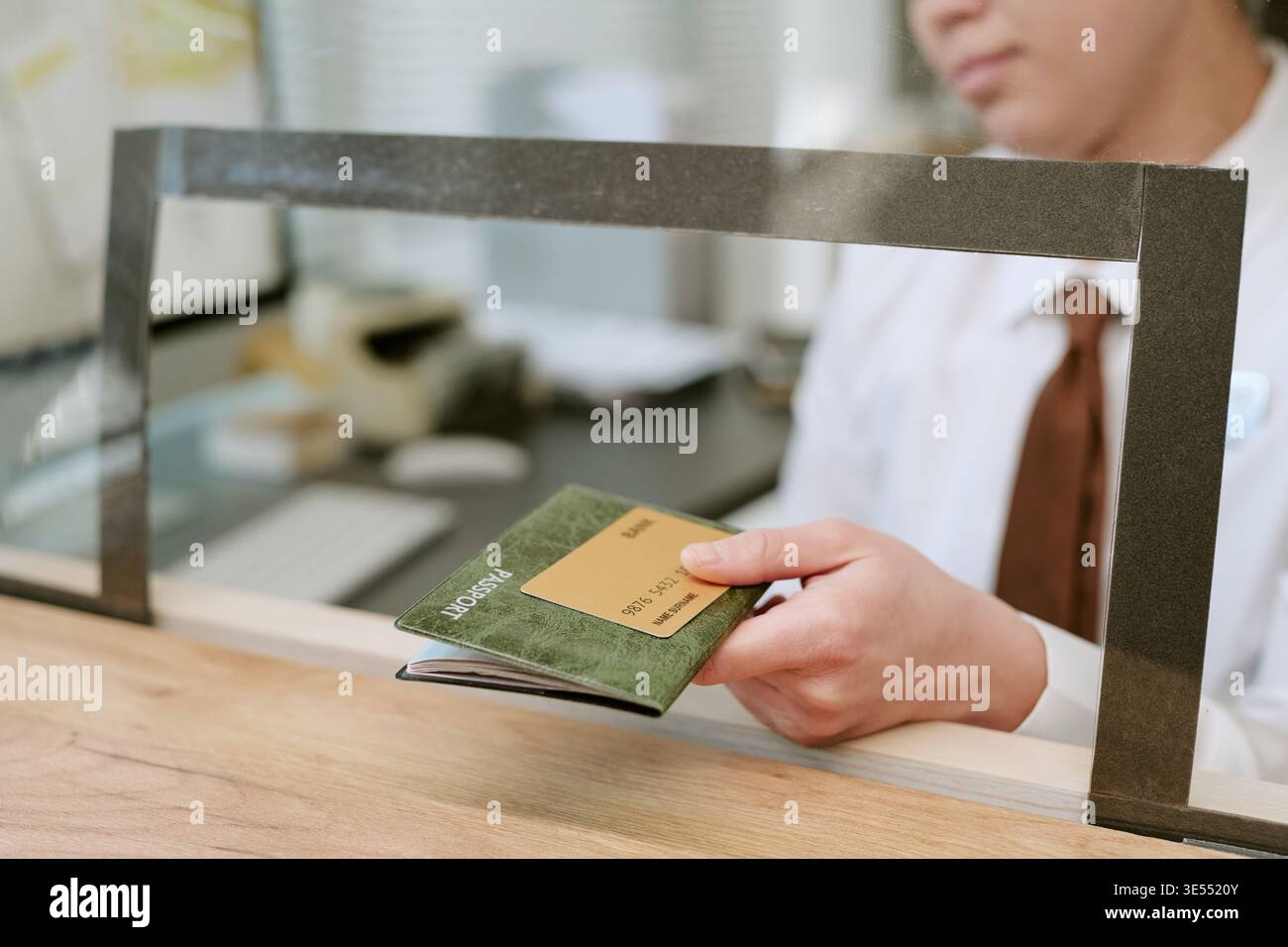 Jeune femme adulte remettant son passeport et sa carte de crédit au comptoir de la succursale bancaire Banque D'Images