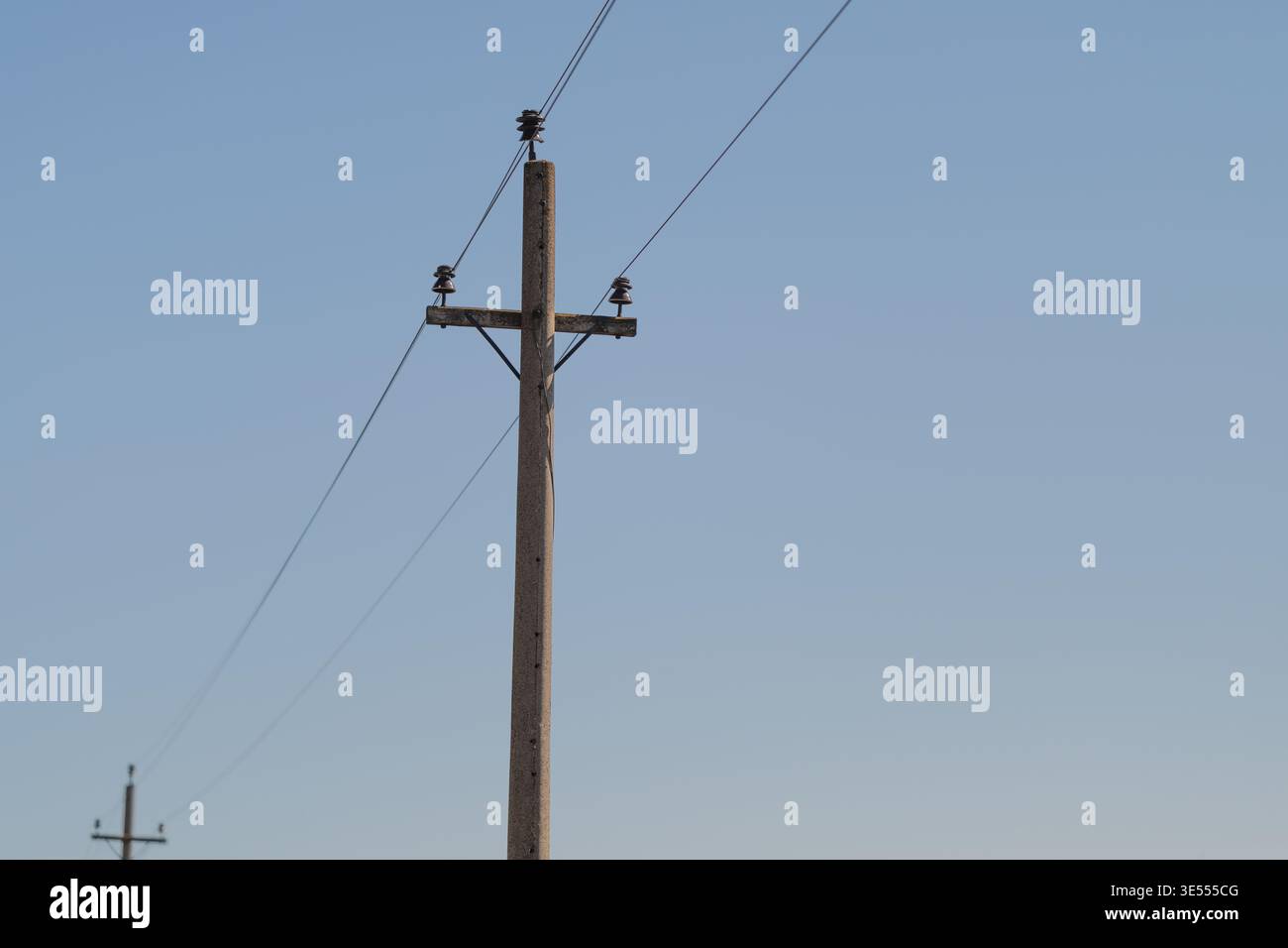 Lignes électriques de poteau de service s'étendant à l'horizon, paysage clairsemé, poteaux jumeaux s'éloignant dans la distance, sentiment de solitude et continuité de l'infrastructure, min Banque D'Images