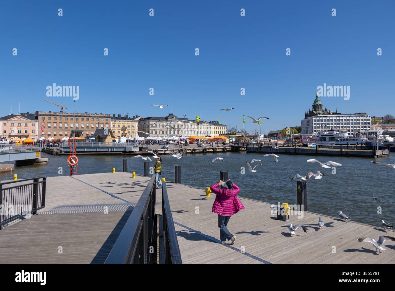 Ville d'Helsinki en Finlande. Touristes asiatiques femmes se nourrissant et s'amusant avec un troupeau de mouettes au port d'Helsinki front de mer. Banque D'Images