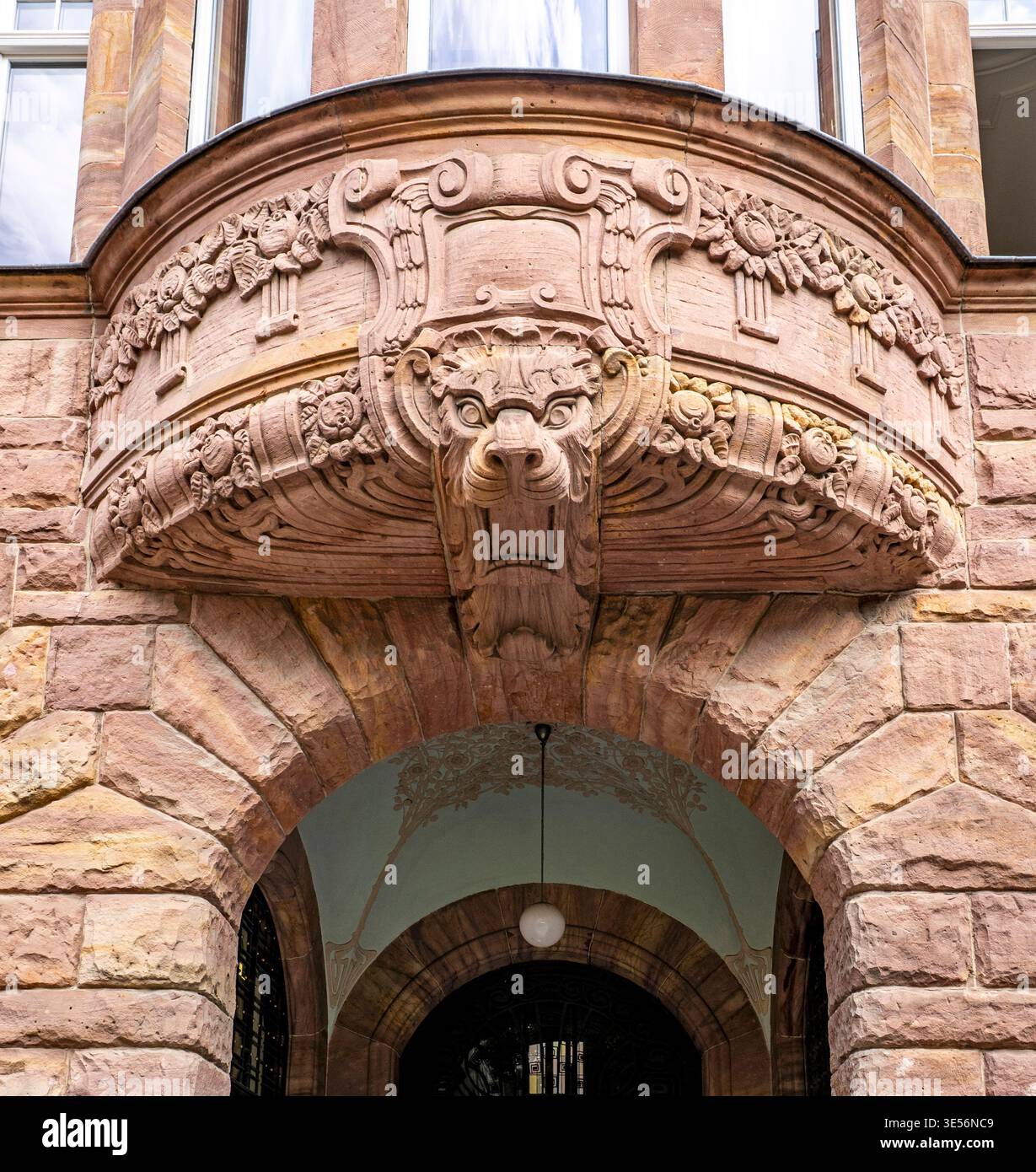 Entrée de bâtiment en pierre ornée avec clé de voûte de lion sculptée, reliefs décoratifs, porte voûtée et façade historique en maçonnerie. Banque D'Images