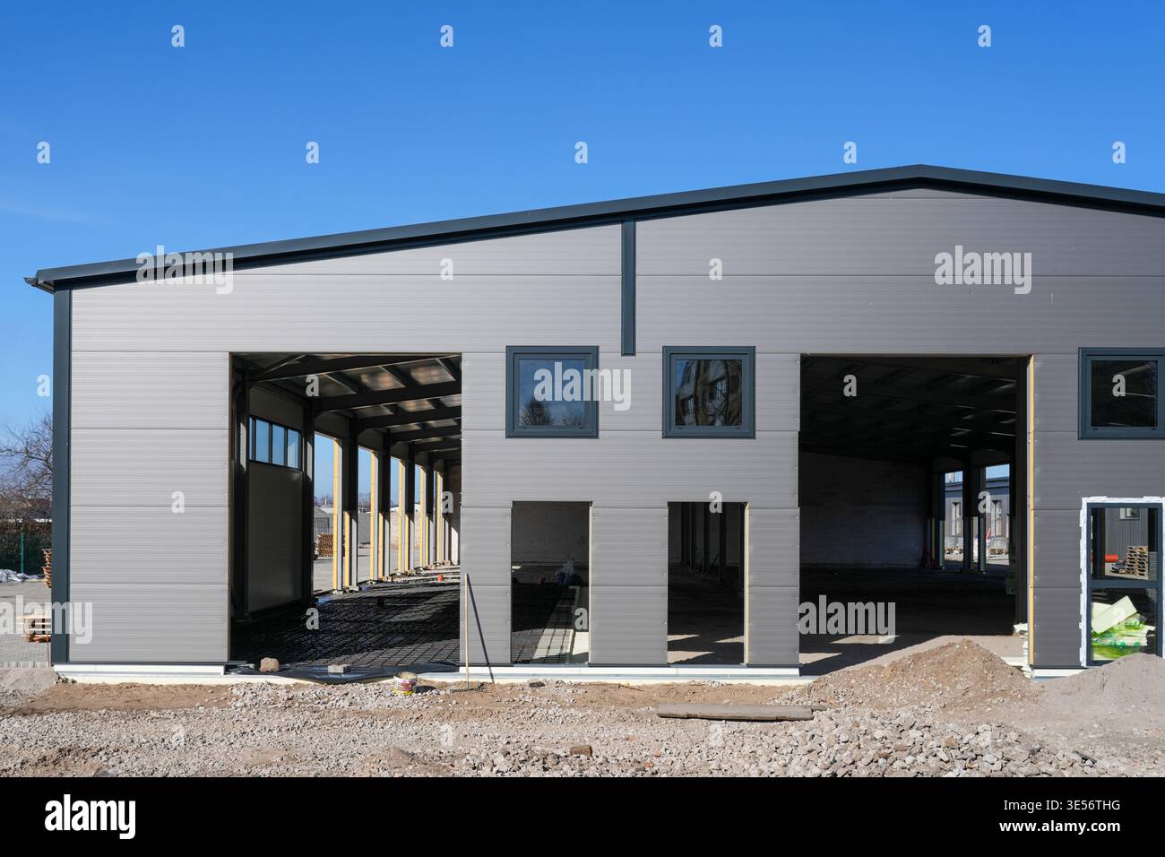Bâtiment industriel moderne en construction avec façade en panneau sandwich métallique et grandes ouvertures Banque D'Images
