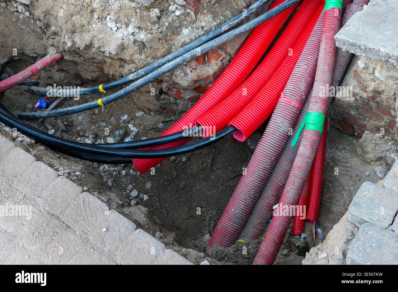 Câbles souterrains et conduits rouges dans les tranchées pendant la construction d'infrastructures urbaines Banque D'Images