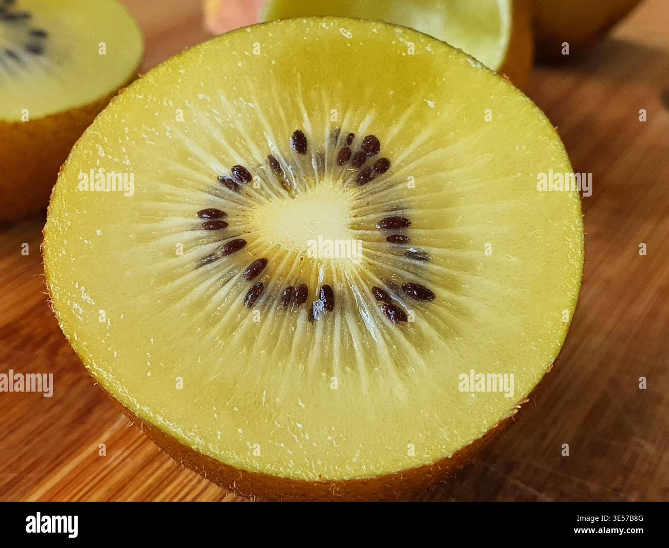 Gros plan macro d'un kiwi doré frais coupé en demi-coupe, révélant une chair jaune-vert éclatante avec un centre blanc et Banque D'Images