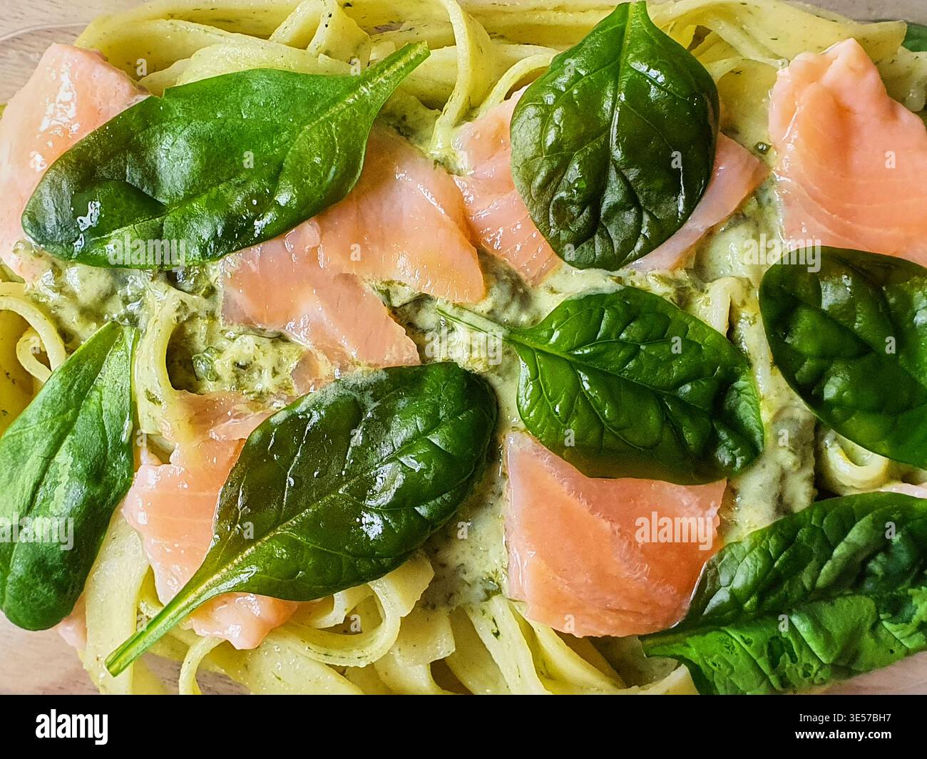 Vue rapprochée du ciel d'un plat de pâtes fraîches avec de larges nouilles en ruban (fettuccine ou tagliatelle) garnies de tranches de saumon fumé et fraîches Banque D'Images