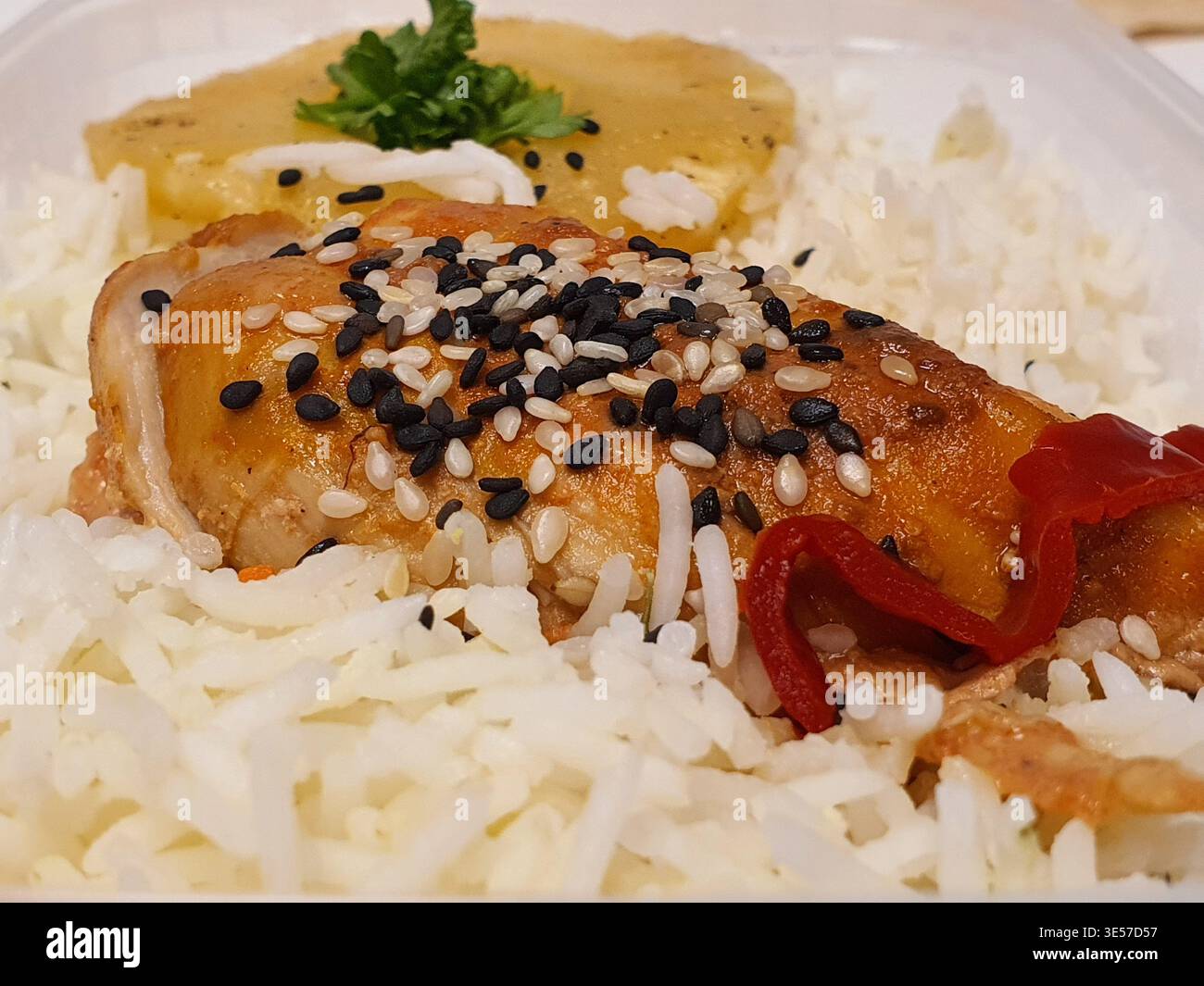 Photographie rapprochée d'un repas préparé avec du poulet rôti brun doré garni de graines de sésame noires et blanches, servi sur un lit de moelleux Banque D'Images