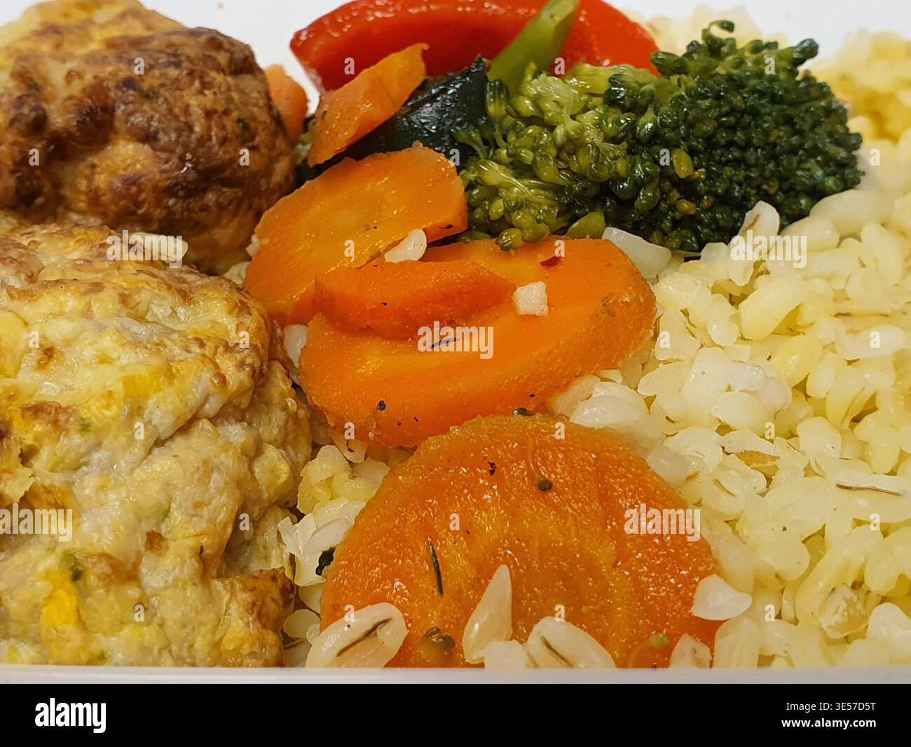 Gros plan macro d'une assiette de repas préparée avec du riz blanc moelleux comme base, accompagné de boulettes de viande ou de galettes dorées à base d'oeuf Banque D'Images