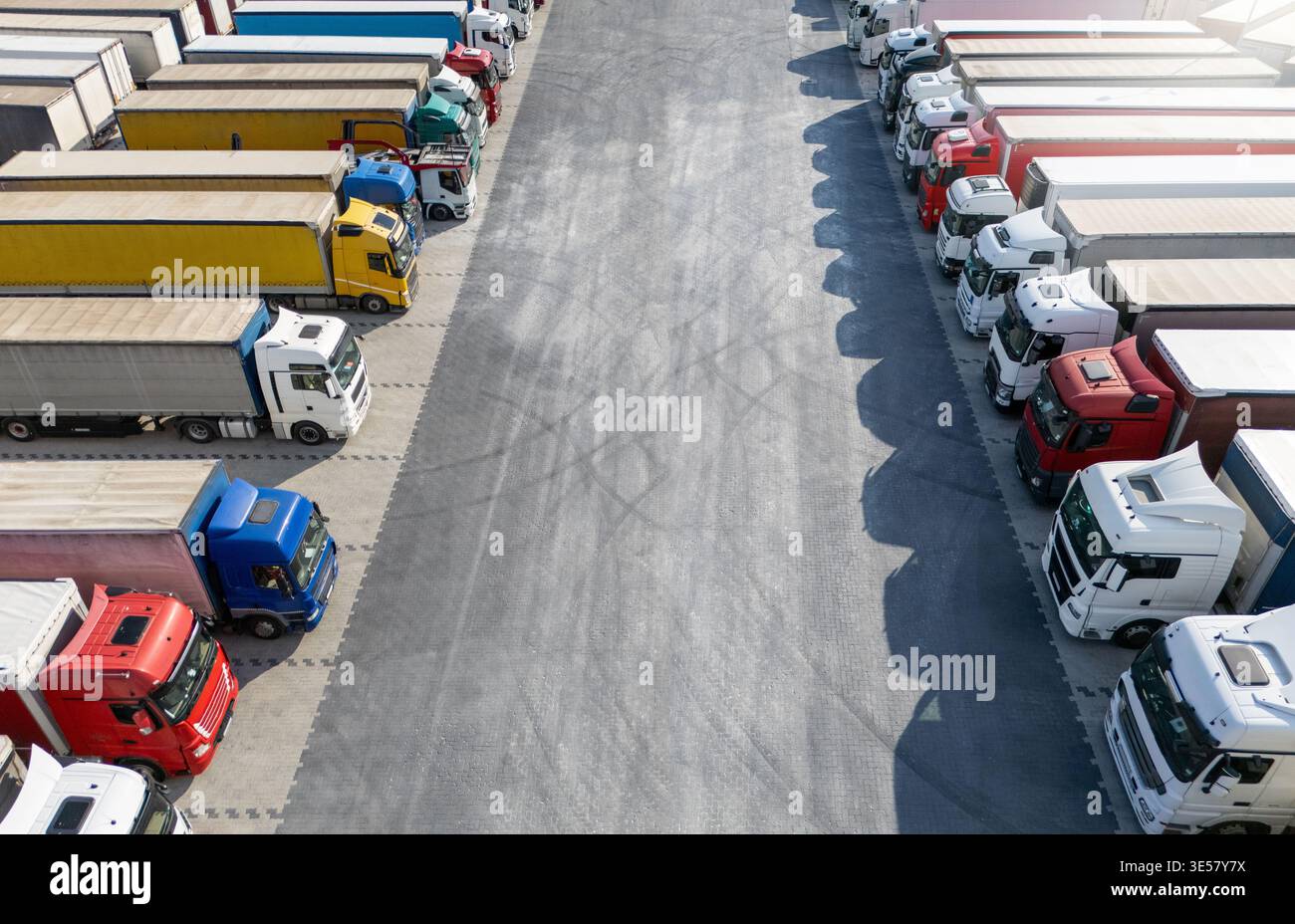 Vue aérienne d'un grand parking pour camions à un centre logistique, avec plusieurs semi-camions commerciaux stationnés en rangées organisées. Banque D'Images