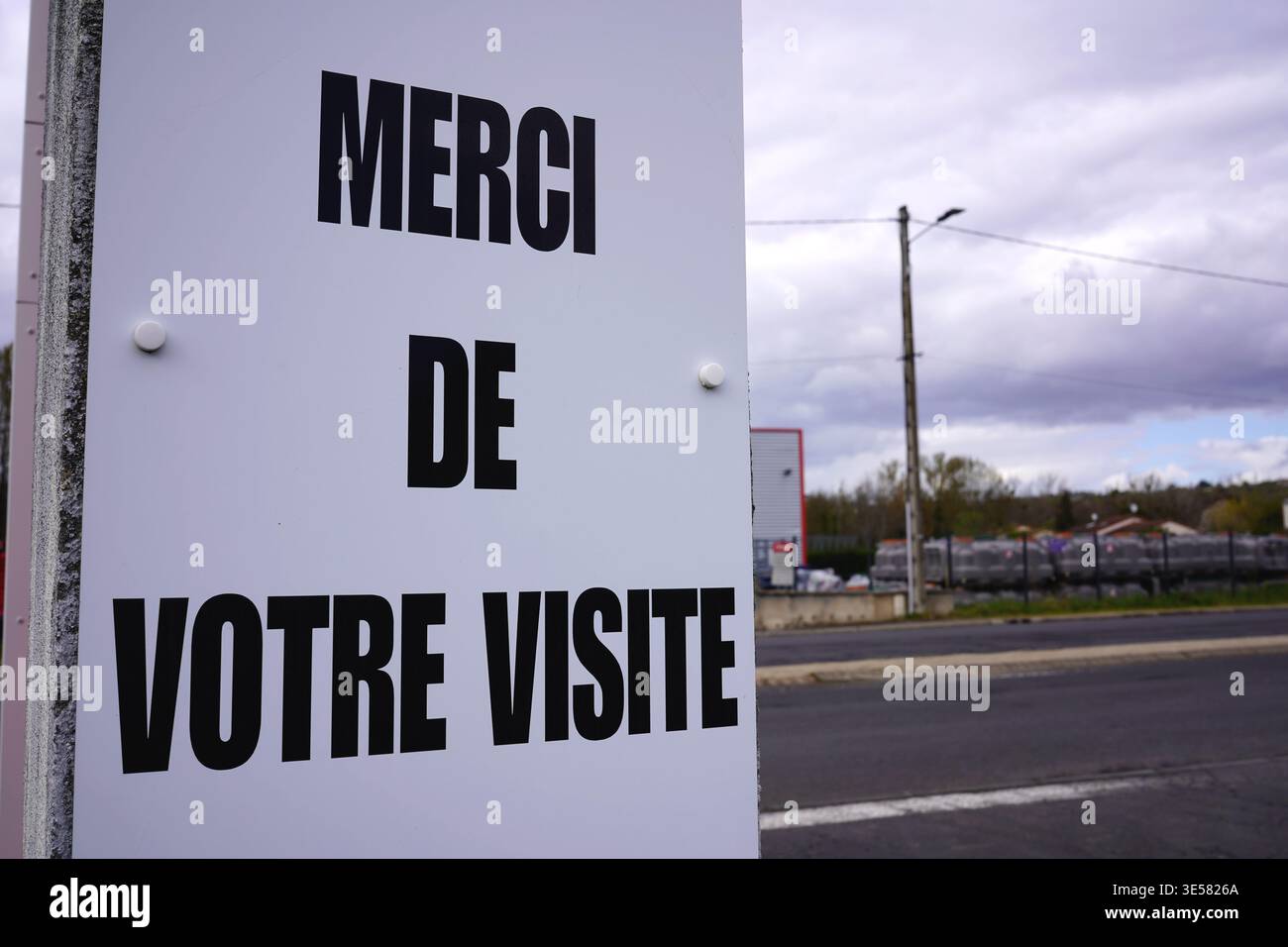 Signe français avec Merci de votre visite texte dans un fond de rue sous un ciel nuageux Banque D'Images