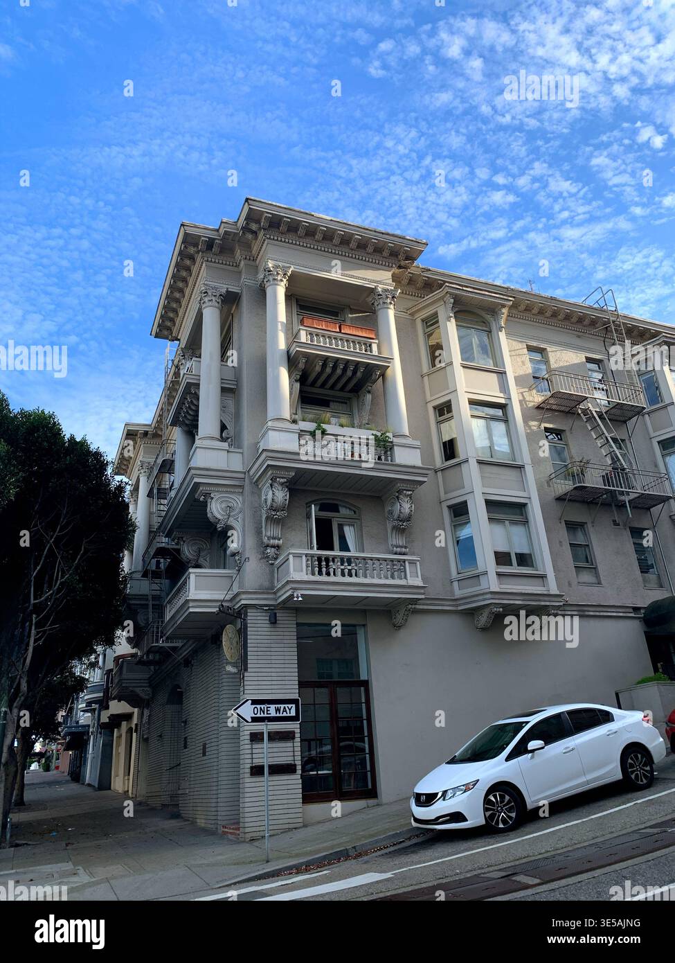 Bâtiment historique de plusieurs étages avec des détails architecturaux ornés, des balcons et un panneau de rue à sens unique, situé dans un cadre urbain sous un ciel bleu Banque D'Images