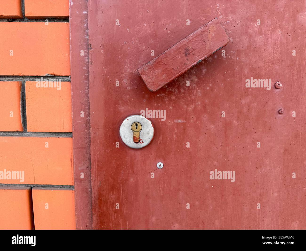 Gros plan d'une porte en métal brun rougeâtre avec un trou de serrure et une poignée. - Image de stock capturée avec un smartphone