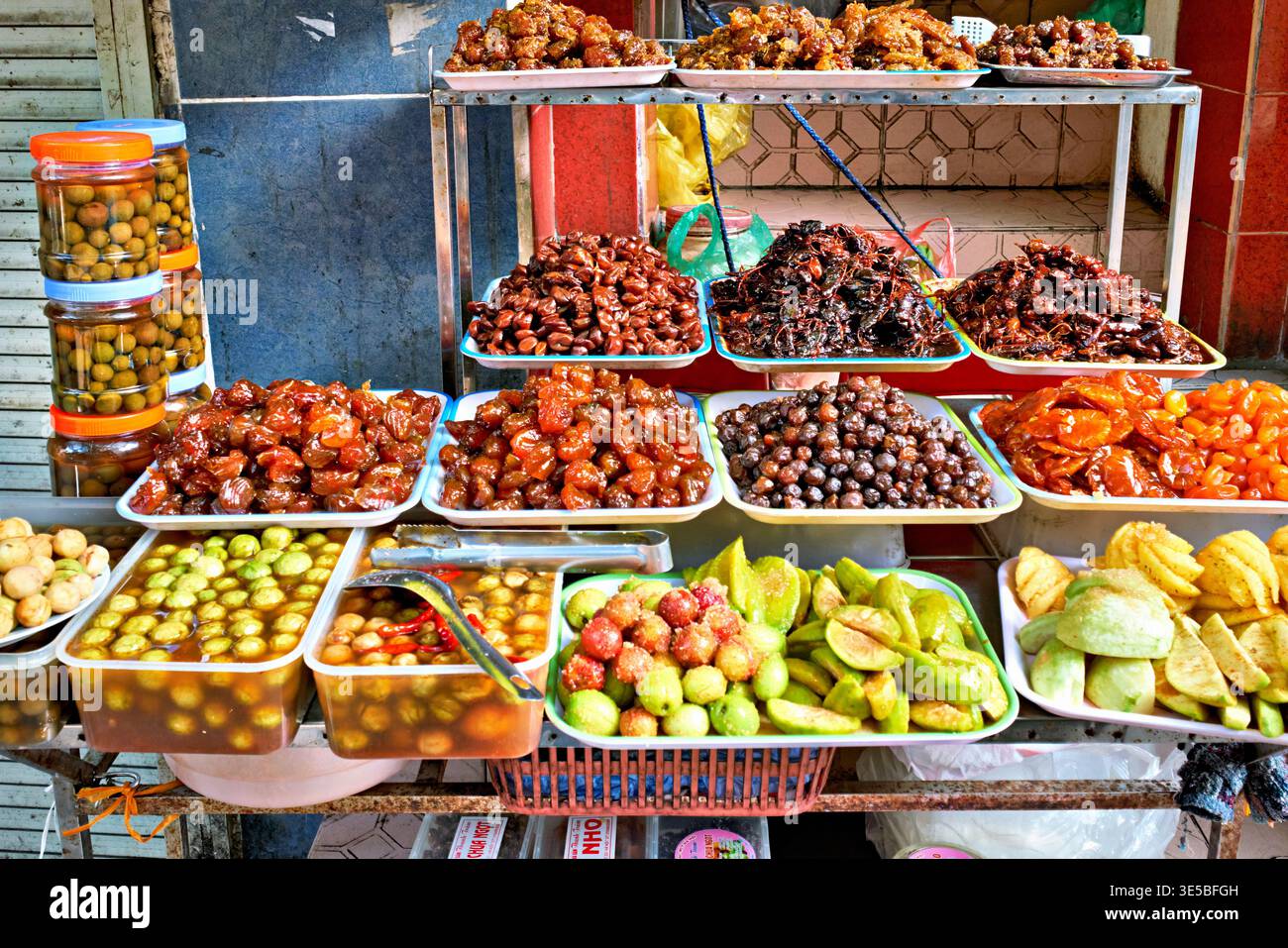 Les vendeurs locaux vendent divers fruits et collations dans un marché animé à Hanoi. Les couleurs et les formes attirent de nombreux clients à proximité. Banque D'Images