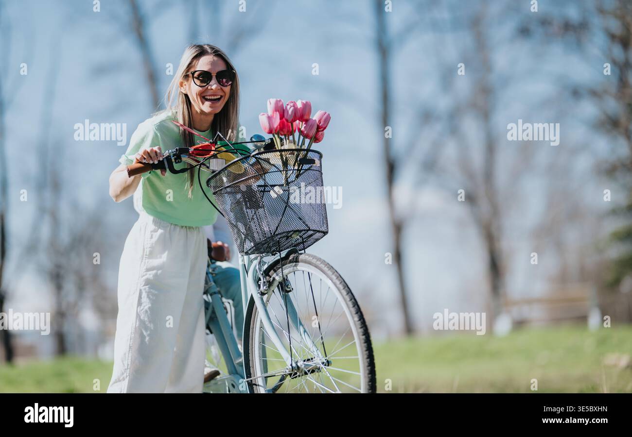 Maman et fille souriantes lors d'une balade à vélo de printemps avec des tulipes dans le panier de vélo Banque D'Images