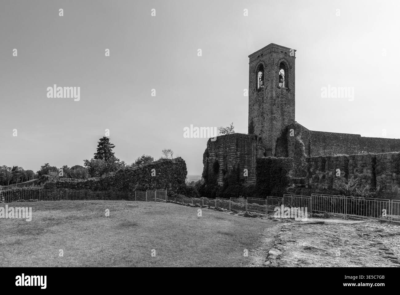 Vue de film d’archive en noir et blanc des ruines du château et du clocher à Cavriana en Lombardie, Italie, composition large montrant de l’herbe usée et des murs cassés. Banque D'Images