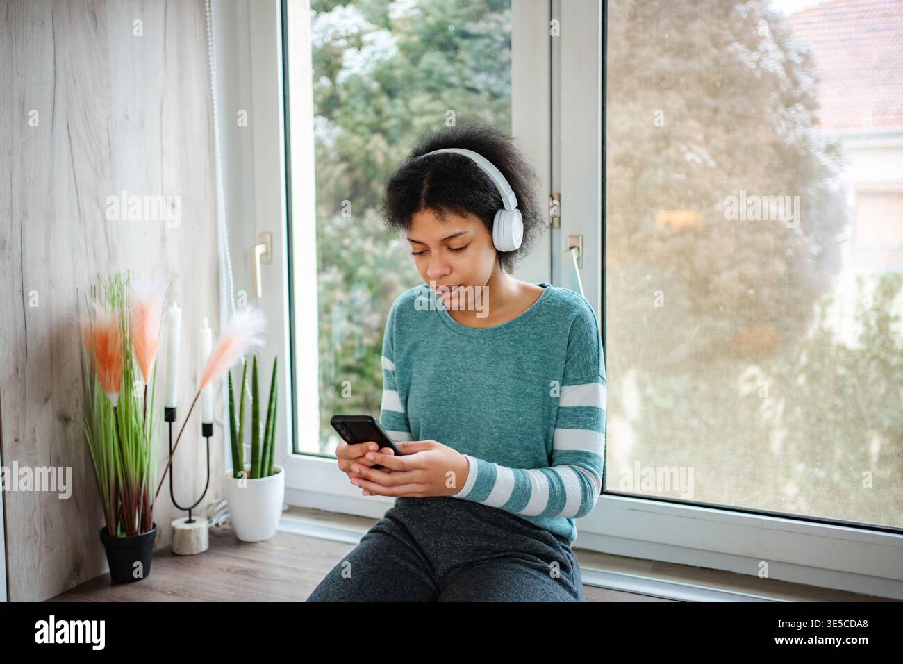 Jeune femme écoutant de la musique sur des écouteurs à l'aide d'un smartphone Banque D'Images
