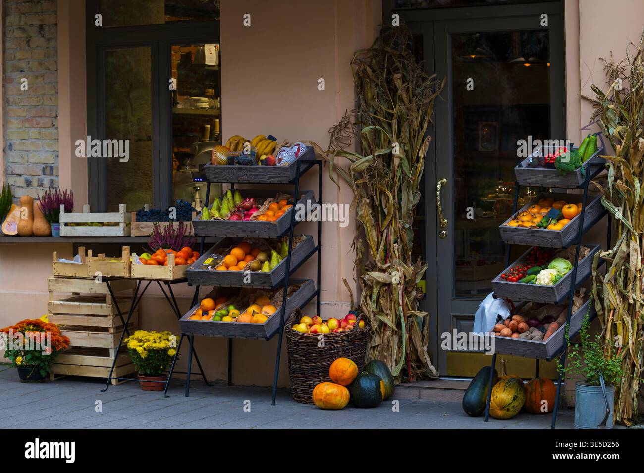 Un stand de produits d'extérieur coloré avec plusieurs caisses en bois et paniers remplis d'une variété de fruits et légumes, y compris des citrouilles, courges, a Banque D'Images