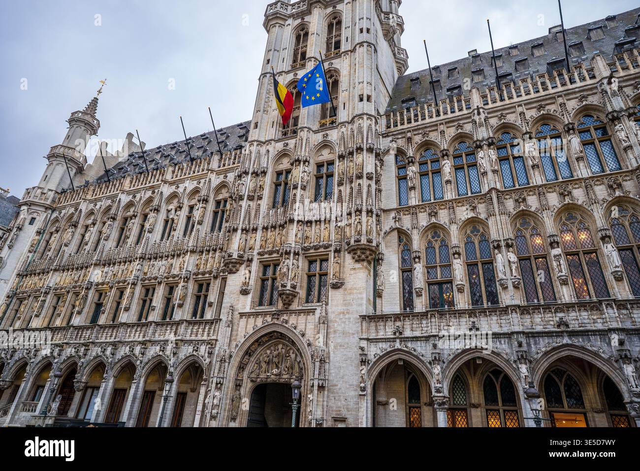 Vue rapprochée et inclinée de la façade de l'hôtel de ville de Bruxelles. L'image met en évidence les sculptures gothiques complexes, les fenêtres pointues, et le belge et E. Banque D'Images