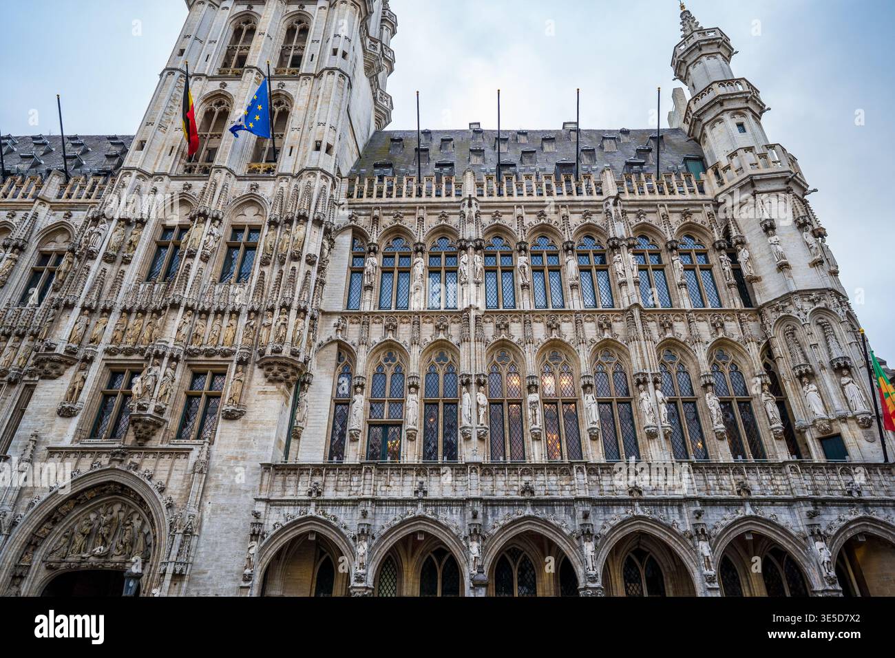 Vue rapprochée et inclinée de la façade de l'hôtel de ville de Bruxelles. L'image met en évidence les sculptures gothiques complexes, les fenêtres pointues, et le belge et E. Banque D'Images
