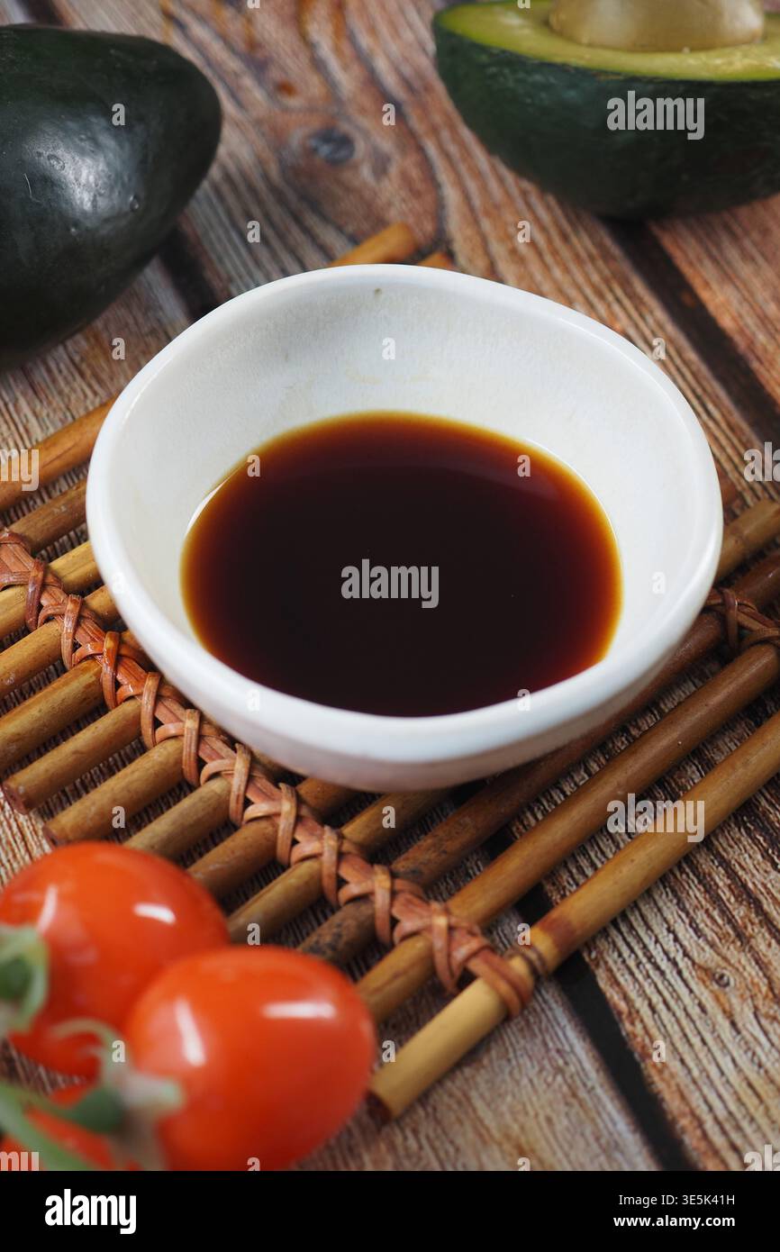 Bol de sauce avec tomates cerises et avocat sur bois Banque D'Images