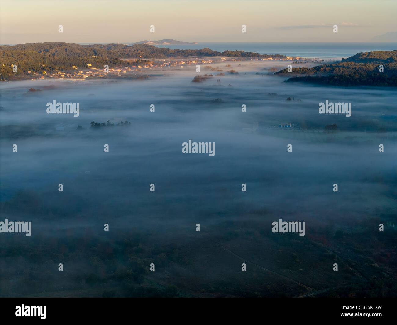 Reathtake panorama aérien d'une vallée brumeuse remplie de brouillard menant à la mer au lever du soleil dans le nord de Corfou, paysage méditerranéen Banque D'Images