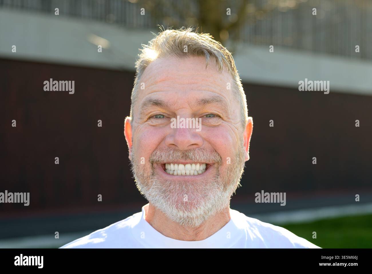 Portrait en gros plan d'un homme mûr heureux souriant largement dans la lumière naturelle du soleil extérieur. Banque D'Images