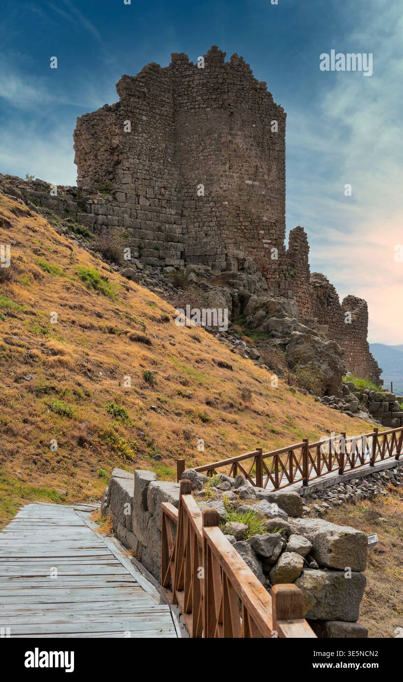Anciennes ruines en pierre de l'Acropole de Pergame sur une colline herbacée sèche avec une passerelle en bois, Bergama, Turquie sous un ciel bleu nuageux Banque D'Images