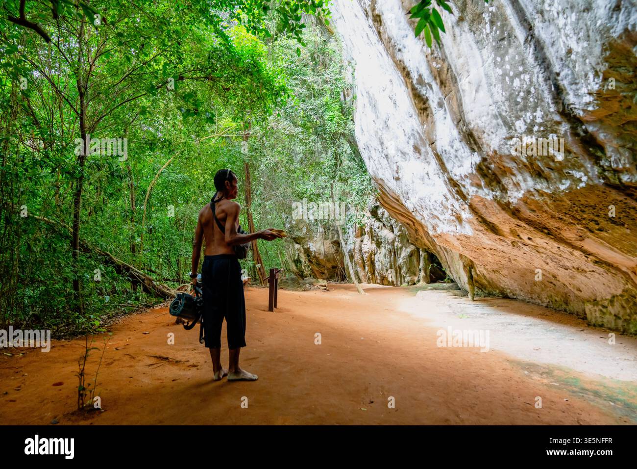 Homme explorant la grotte de la jungle luxuriante en thaïlande Banque D'Images