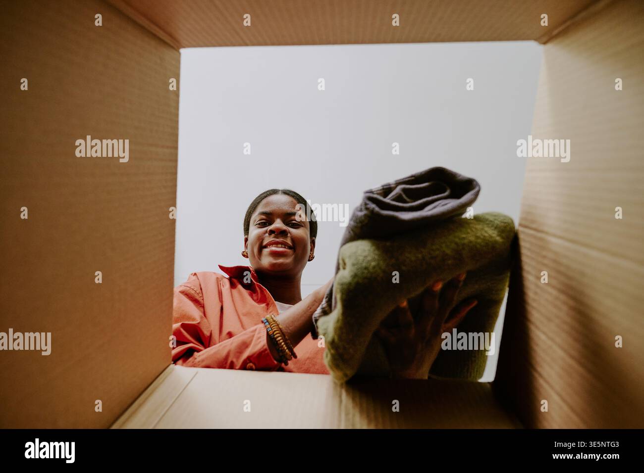 Portrait de femme noire emballant des vêtements pliés pour la commande en ligne Banque D'Images