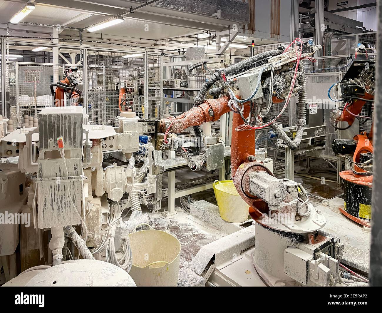 Bras robotisé industriel recouvert de barbotine en céramique blanche dans une usine de fabrication d'appareils sanitaires Banque D'Images