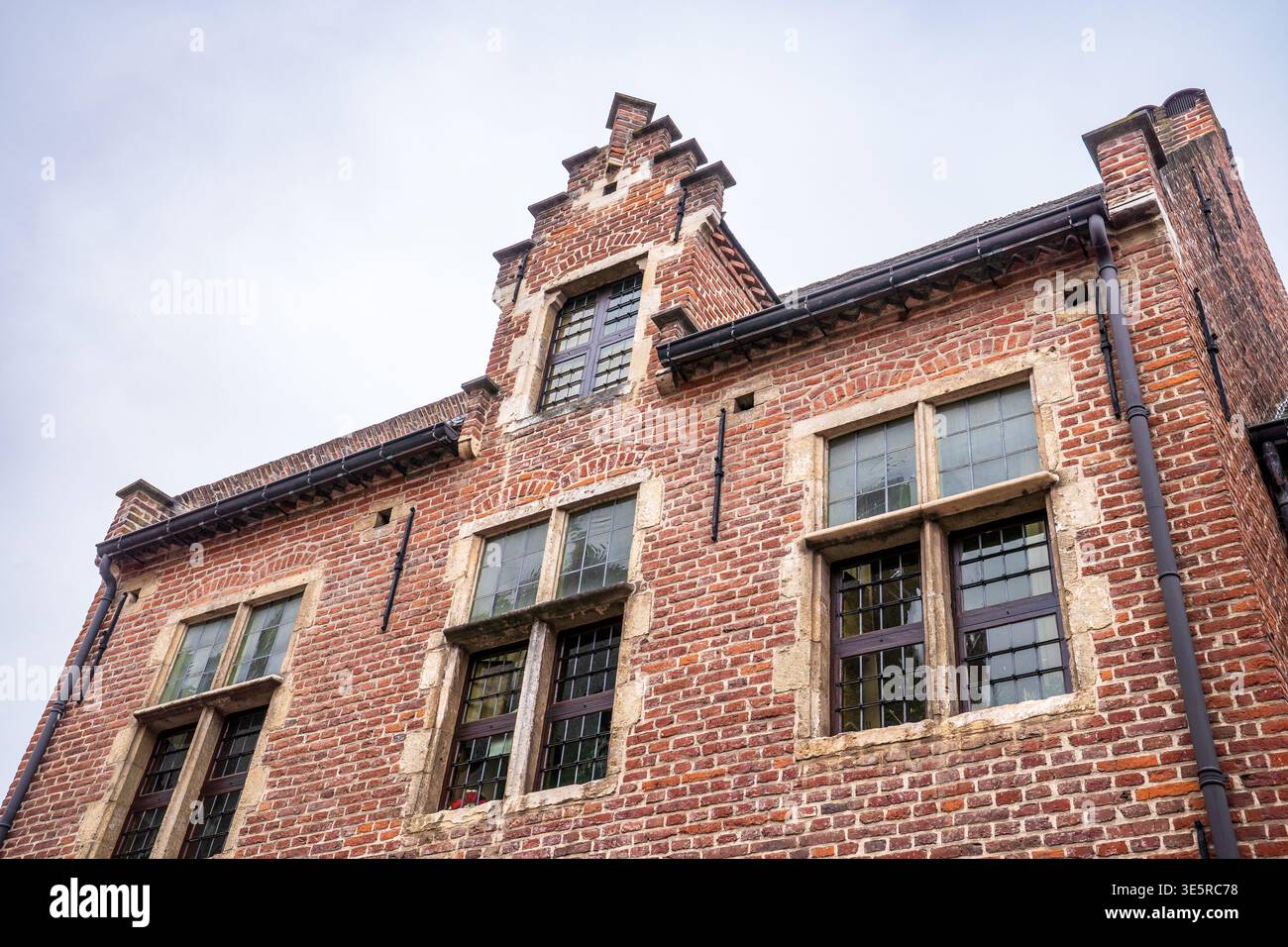 Détail architectural dans le Groot Begijnhof de Louvain, un site de l'UNESCO. Façade en briques rouges avec pignon flamand à gradins typique et crocs encadrés de pierre Banque D'Images
