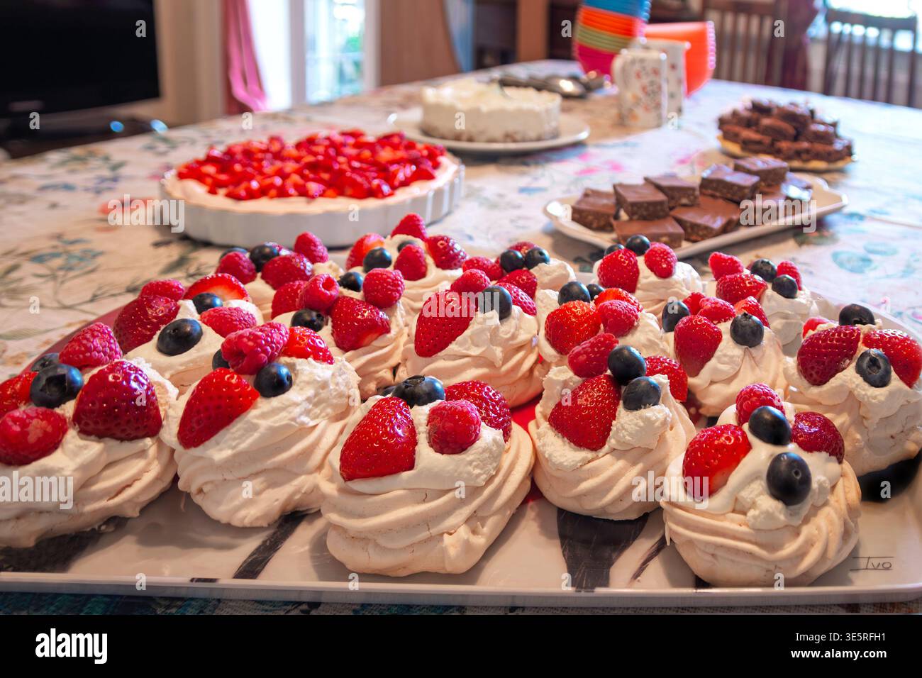 Table de fête avec divers desserts, y compris pavlova garnie de brownies au chocolat aux fraises et aux myrtilles et une tarte aux fruits Banque D'Images