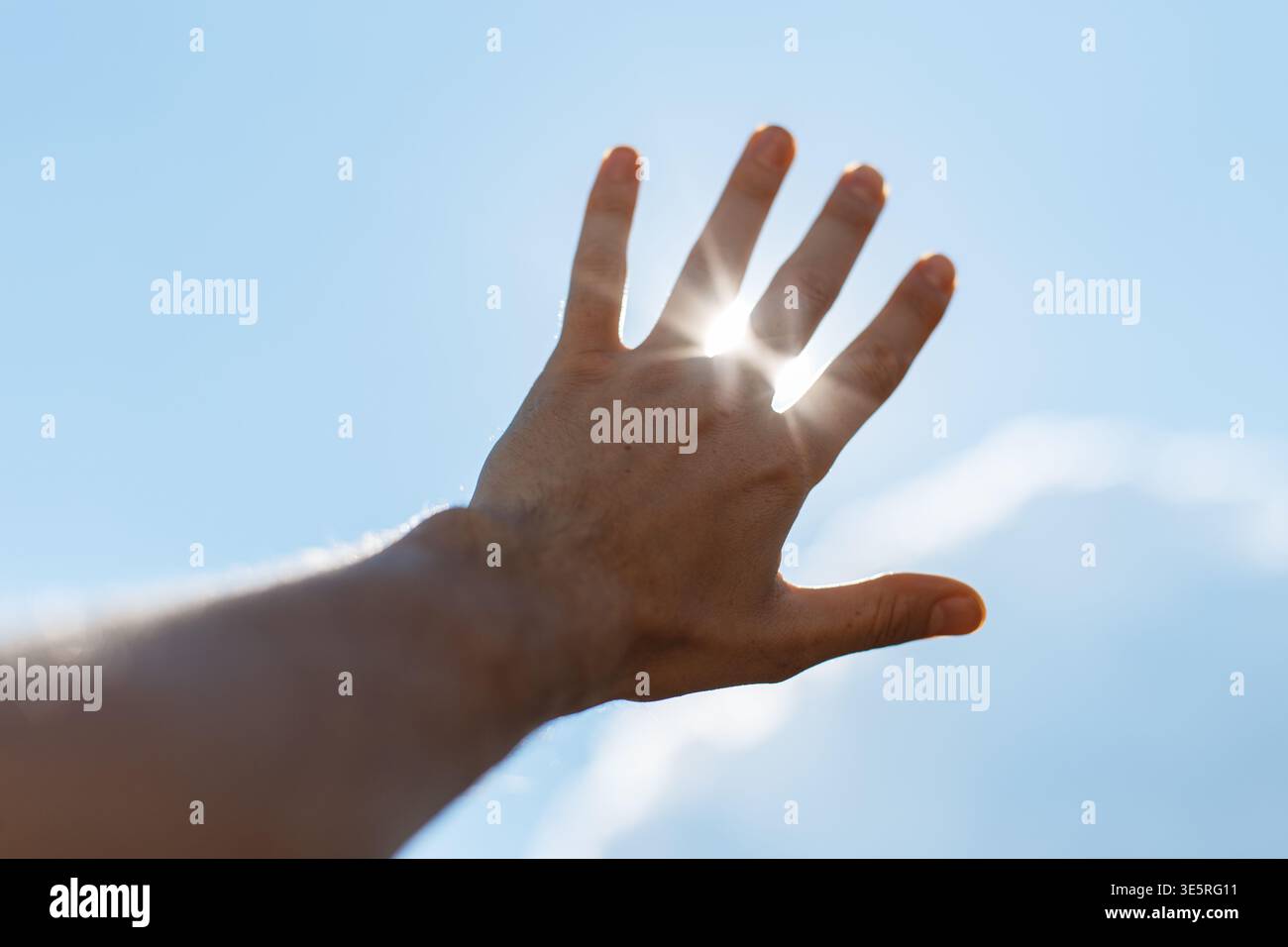 L'homme leva la main vers le soleil et les rayons du soleil brillent à travers ses doigts. Liberté, concept Banque D'Images
