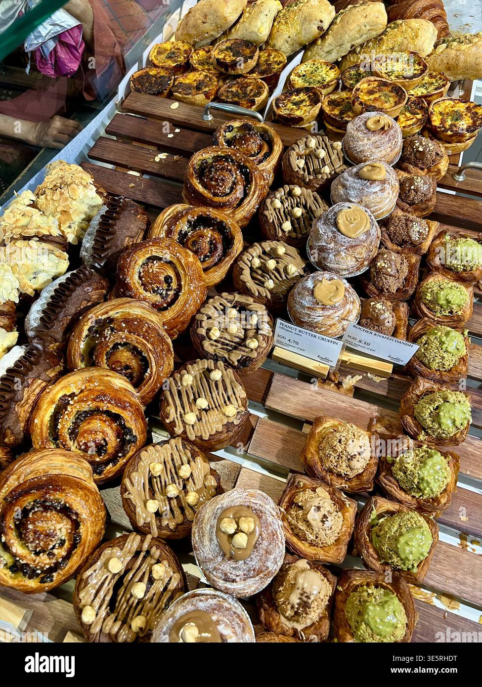 Pâtisseries colorées aux saveurs variées dans un rack en bois d'une boulangerie - Image de stock capturée avec un smartphone