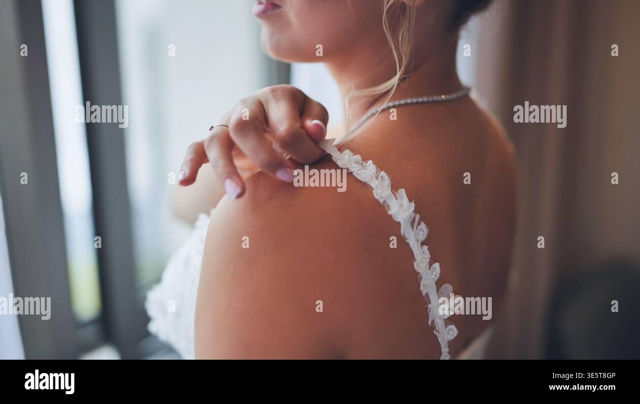 Gros plan de la mariée ajustant la sangle de dentelle délicate sur son épaule. Banque D'Images