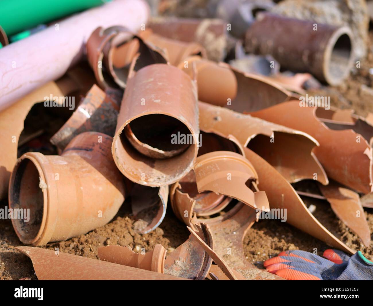 Tuyaux de drainage en céramique cassés sur le chantier de construction, tas de tuyaux d'égout en argile brisés, débris de démolition industrielle, fragmen de tuyau en terre cuite orange Banque D'Images