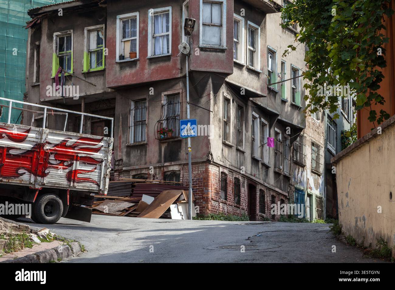 Un bâtiment résidentiel de l'époque ottomane altérée sur un coin de rue arrière étroite avec un camion stationné et des débris dispersés à Istanbul, Turquie Banque D'Images