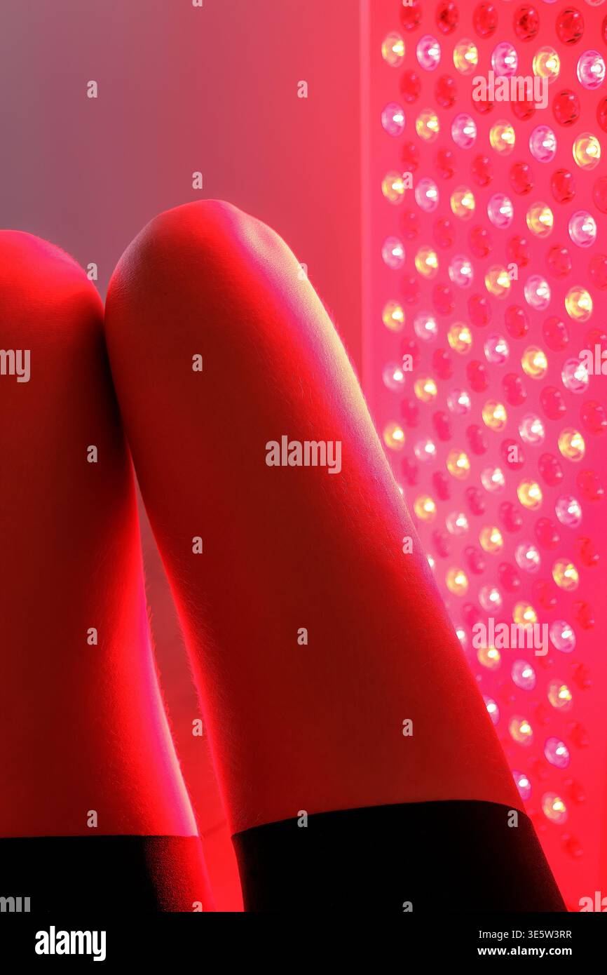 Femme faisant une thérapie de lumière rouge sur sa jambe inférieure Banque D'Images