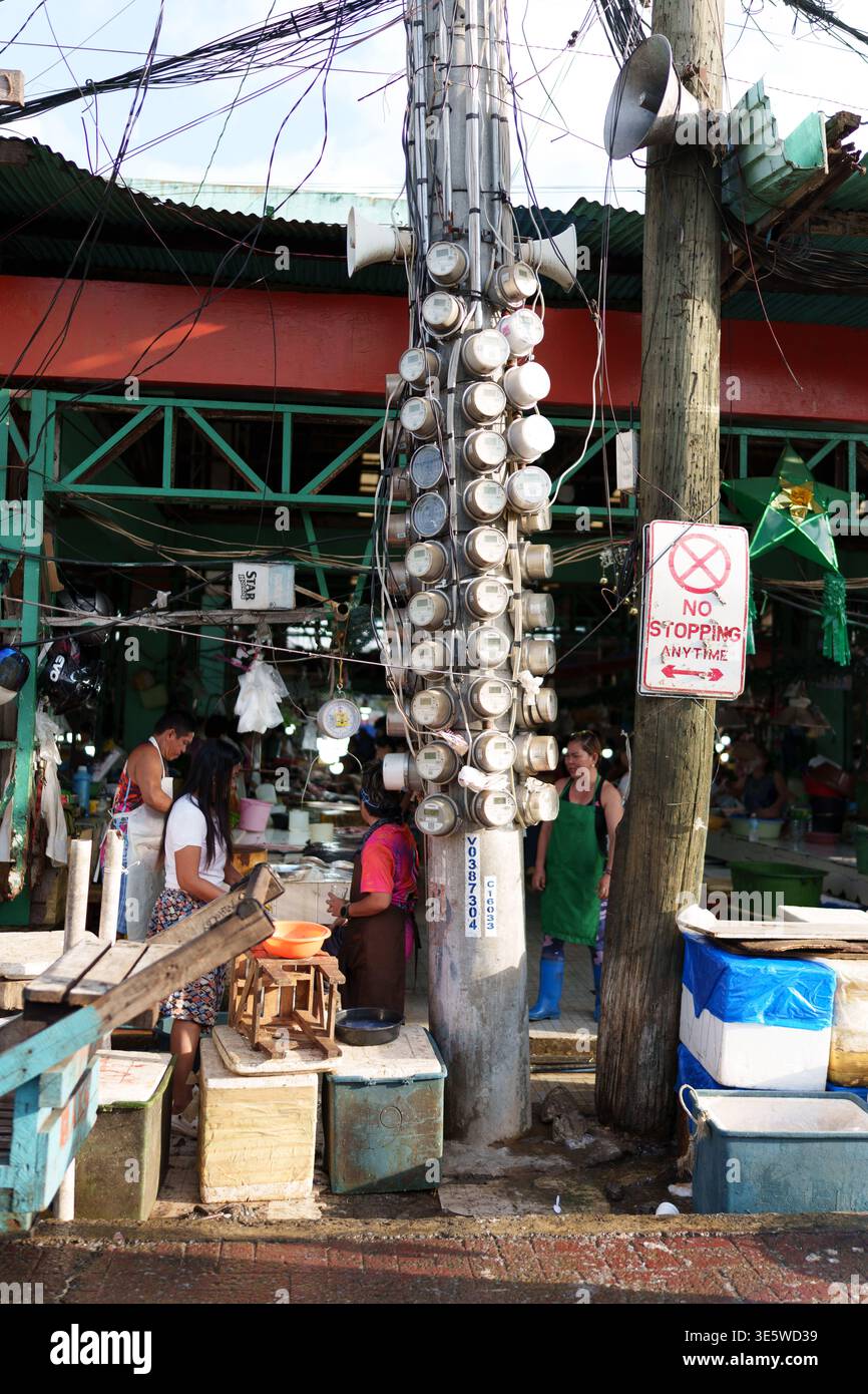 Grappe de compteurs de puissance électrique montés sur un poteau de service public en dehors du marché du carbone Cebu City Philippines montrant l'approvisionnement en électricité partagé dans la zone urbaine. Banque D'Images
